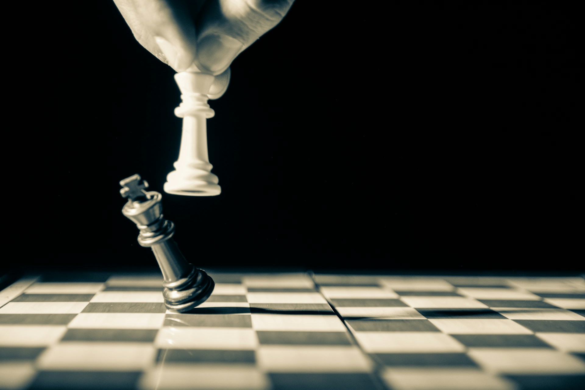 check mate-unsplash A hand holding white chess piece, knocking down opposing king.